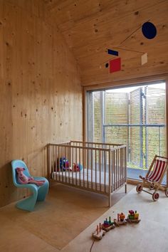 a baby's room with a crib, rocking chair and large window in the corner