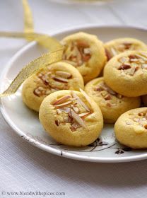 a plate full of almond cookies on a table with a yellow ribbon around the edge