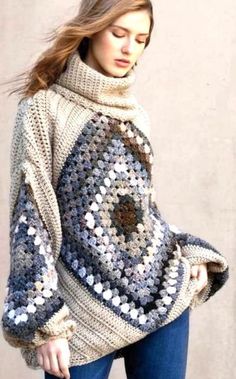 a woman wearing a crocheted sweater and jeans is standing in front of a wall