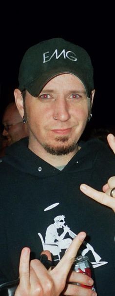 a man in a black shirt and hat making the peace sign