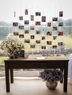 a table with pictures and flowers on it in front of a window that is decorated with photos