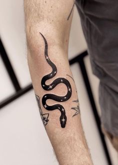 a man's arm with a black snake tattoo on the left side of his arm