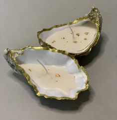 two oyster shell candles sitting on top of each other in front of a gray background