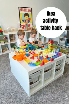 two young boys playing with toys in a playroom that is filled with storage bins