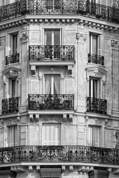 a black and white photo of a building with balconies on the top floor