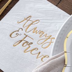 there is a napkin with gold lettering on it and a white plate next to it