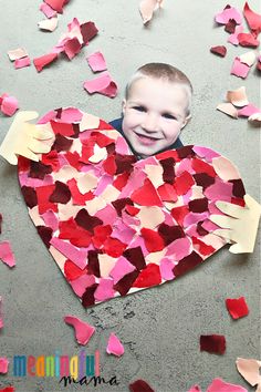 a young boy holding up a heart made out of paper and colored confetti