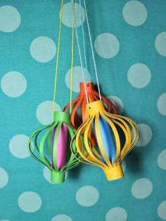 three colorful paper lanterns hanging from strings on a polka dot wall