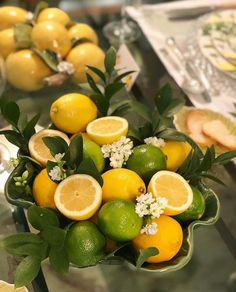 there are many lemons and limes in the bowl on the glass table top