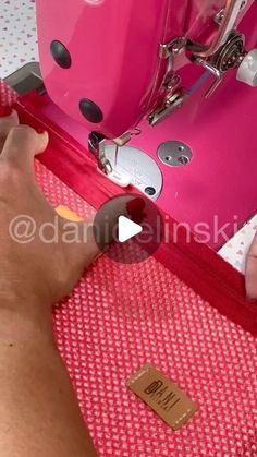 someone is using a pink sewing machine to sew on the fabric with their hands