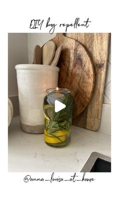 a glass jar filled with green plants sitting on top of a counter next to a cutting board