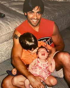 a man sitting on top of a couch holding a baby next to another young child