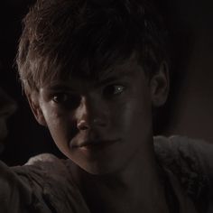 a young boy is staring at another person in the dark, with one hand on his shoulder