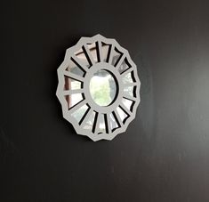 a circular mirror mounted to the side of a black wall next to a white door