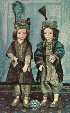 two dolls standing next to each other on a rug