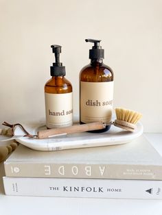 two soap dispensers sitting on top of a book next to a brush