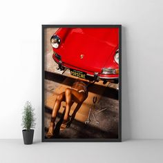 a red car parked next to a potted plant on top of a wooden floor