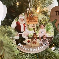 a christmas ornament hanging from a tree with two children and santa clause on it