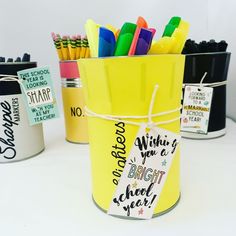 three buckets with pens and markers in them on a white table next to each other