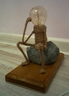 a light bulb sitting on top of a rock with rope wrapped around it's legs