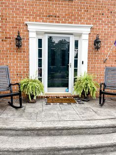 two chairs sitting on the side of a brick building next to a door and steps