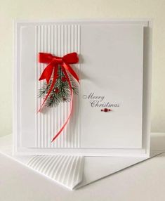 a christmas card with a red bow and holly on the front, sitting on top of a white table