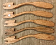 four wooden spoons are lined up on a tablecloth with buttons in the middle