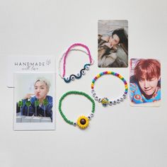 various bracelets are displayed on a white surface next to an album and photo card