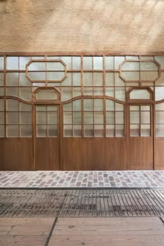 an empty bench in front of a building with glass panels on the wall and floor