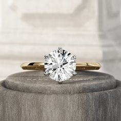 a diamond ring sitting on top of a stone pedestal