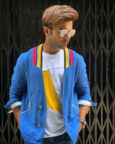 a man with sunglasses on his head is standing in front of a gate and looking down