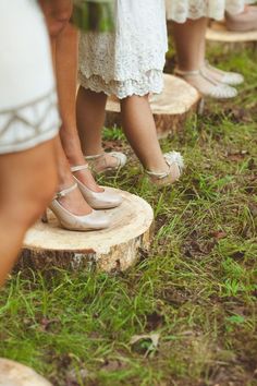 several people standing on top of wooden slices in the grass, with one person wearing white shoes