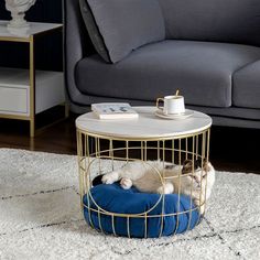 a cat laying on top of a blue pillow in a cage next to a couch