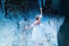 a young ballerina is dancing in the rain with her arms up and hands out