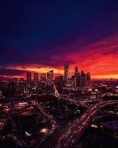 the city skyline is lit up at night with cars driving down it's street