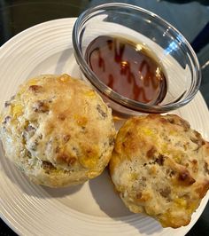 two biscuits on a plate next to a bowl of sauce