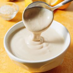 a spoon is in a white bowl filled with yogurt and oranges on the table