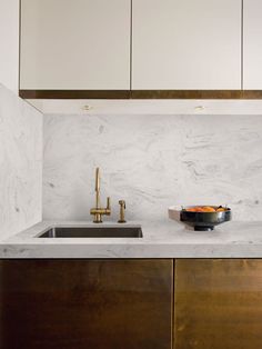 a kitchen with marble counter tops and brass faucets