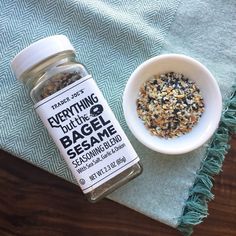 a bowl of seeds next to a bottle of bagel seasoning