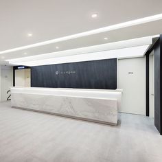 an empty lobby with white marble counter tops and black wall behind the reception desks