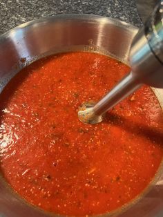 a metal bowl filled with red sauce on top of a counter