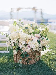 a basket filled with white flowers sitting on top of a lush green grass covered field