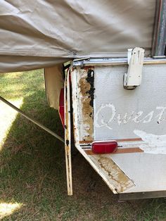 an old rusted out camper with the word quest painted on it's side