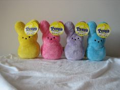 three peeps bunny stuffed animals sitting next to each other on a white bed sheet