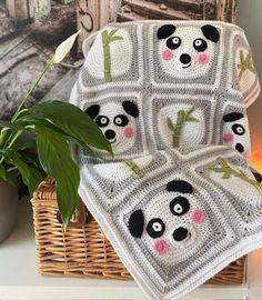 a crocheted panda bear blanket sitting on top of a table next to a potted plant