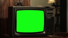 an old television with a green screen on a table in front of a lamp and mirror