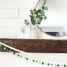 a white fireplace mantle with a mirror and green garland on the mantel above it