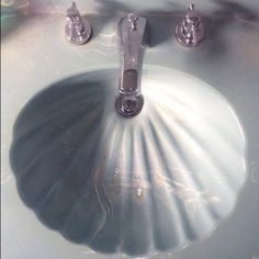 a white sink with two chrome faucets on it's sides and a mirror behind it