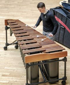 a man playing an xylon on top of a musical instrument in a room