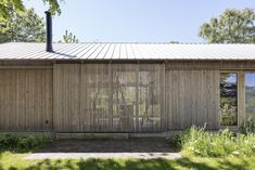 a house with wooden slats on the outside and windows in the inside, surrounded by grass